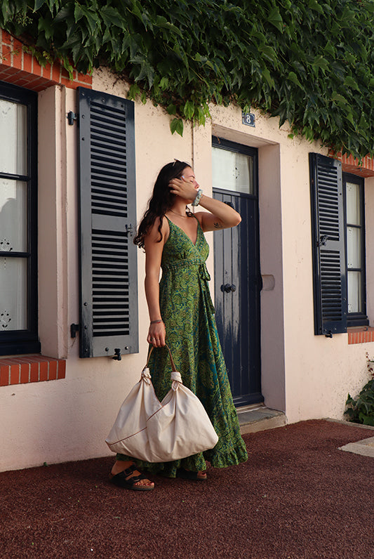 a woman in a green dress holding a white bag
