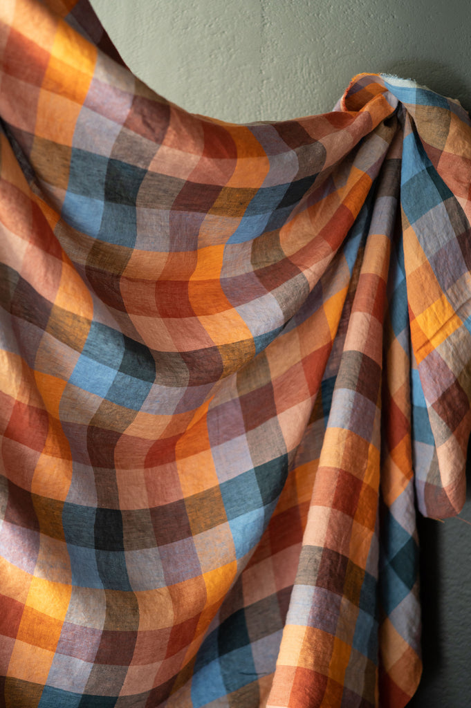 an orange and blue checkered blanket hanging on a wall